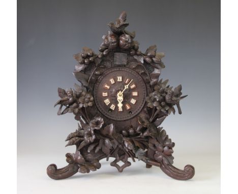 An early 20th century and later Black Forest carved wood wall bracket clock, the case carved with birds, fruit and flowers, w