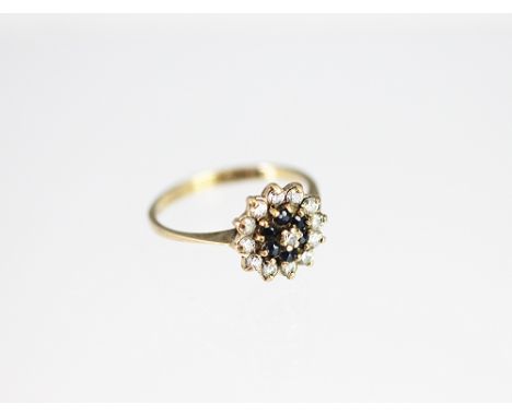 A sapphire and diamond target ring, designed as a central diamond within a surround of sapphires and an outer surround of fur