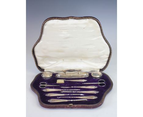 A cased silver manicure set, 'CD' London 1916, comprising; buffers, jars, tools, scissors, a brush etc, within fitted leather