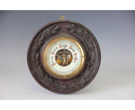 A Victorian carved walnut aneroid barometer, with ceramic dial and oak leaf and acorn frame, 27cm diameter