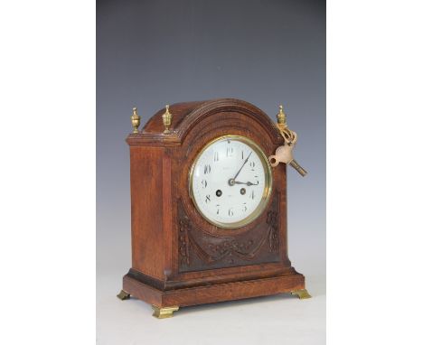 An Edwardian carved oak mantel clock, with Arabic enamel dial and movement striking on a gong, 28cm