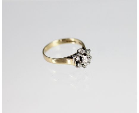 A diamond set flower cluster ring, the seven stone diamond cluster all set in white metal to the plain shoulders and pale 9ct