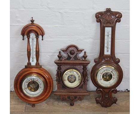 A late Victorian carved oak aneroid barometer, 35cm, with two walnut barometers with inset thermometers (3)