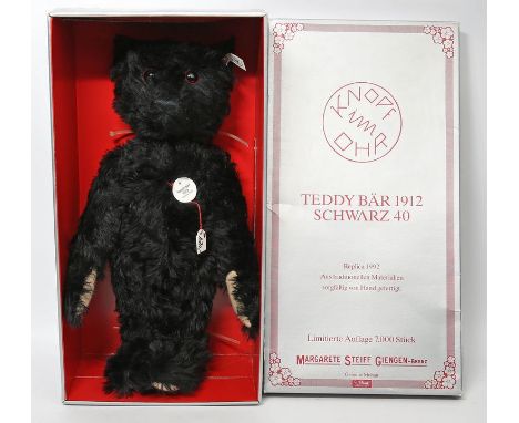Steiff-Teddy 1912, schwarz. Replika 1992 mit Knopf, Fahne, Schild und Zertifikat, Nr. 2853/7000. H. 40 cm. Im Originalkarton.