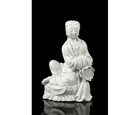 A MOLDED DEHUA BLANC DE CHINE MODEL OF A SEATED GUANYIN WITH A LOTUS  China, Modern  The Goddess of Mercy is depicted seated 