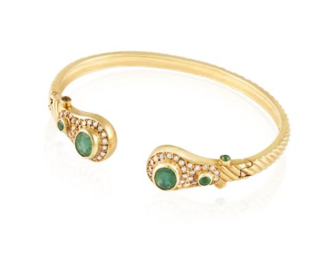 AN EMERALD AND DIAMOND BANGLEThe reeded gold bangle with two terminals set with oval-shaped emerald, embellished with single-