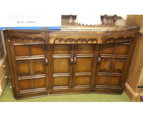 A Jacobean Revival Sideboard of Bow Form; with drawers and cupboards, along with a stool.