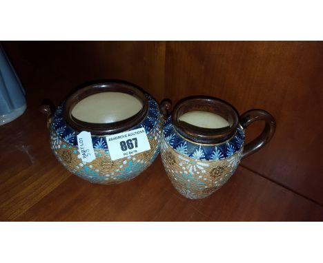 A Doulton Lambeth Stoneware Sugar Bowl and Cream Jug with typical decoration on a blue ground (2).