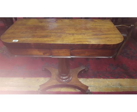 A Regency Mahogany Foldover Card Table; raised on an octagonal vase shaped pillar and platform base with lions paw feet.