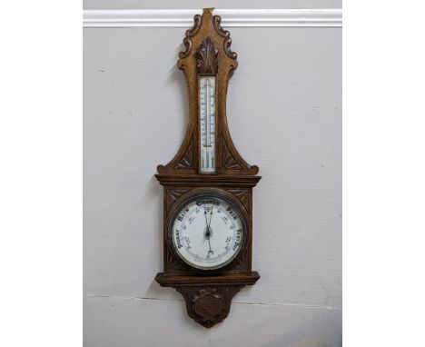 An early 20th century oak barometer with carved ornament and a thermometerLocation:
