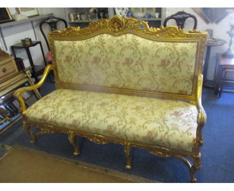 A Louis XV style ornate gilt sofa having floral scroll decoration, shell to the top and on cabriole legs, 129cm h x 174cm wLo