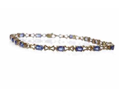 SAPPHIRE BRACELETset with oval sapphires, each approximately 5mm long and interspaced by pierced bow motif links, 19cm long, 