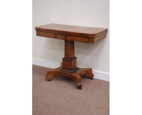 Regency brass inlaid rosewood card table, rounded rectangular hinged top, raised on stepped obelisk column, cruciform base re