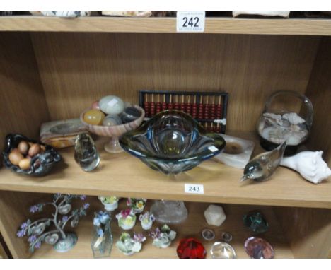 A shelf of glass items, stone eggs, treen eggs etc