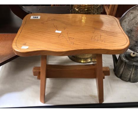 A light oak stool with horse carving