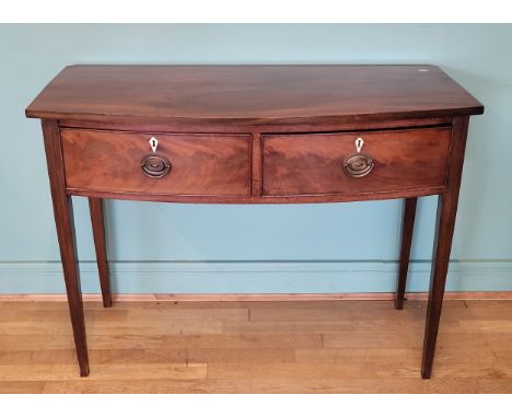 A George IV mahogany bow fronted console table, having two deep drawers with brass swing handles, raised on tapered legs.W102