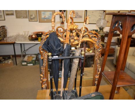 A cast iron and brass six division stick stand with four umbrellas 