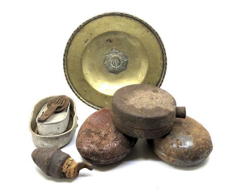 A collection of military items, comprising:- a brass regimental charger, three battlefield find waterbottles, a spoon and for