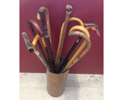 10 vintage walking sticks in a copper stick stand to include tribal carved and a fist marked Pitcairn 