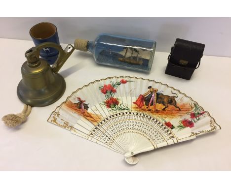 A tray of assorted misc. items. Comprising; a brass bell, a hand painted fan, cased vintage hymn books, a ship in a bottle & 