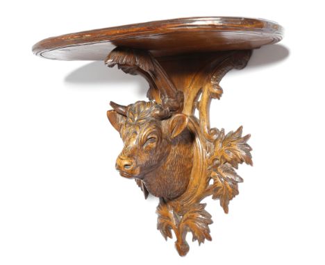 A late 19th century Black Forest carved limewood wall bracket, with a bull's head trophy mount support and carved with leaves