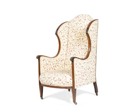 A late Victorian mahogany wing armchair, inlaid with satinwood banding, the frame carved with leaves, on square tapering legs