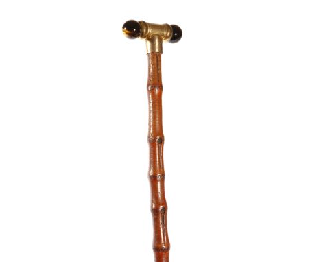 A George V swagger stick, the gilt metal handle with twin tiger's eyes and inscribed 'C. D. XMAS 1916', with a bamboo shaft, 