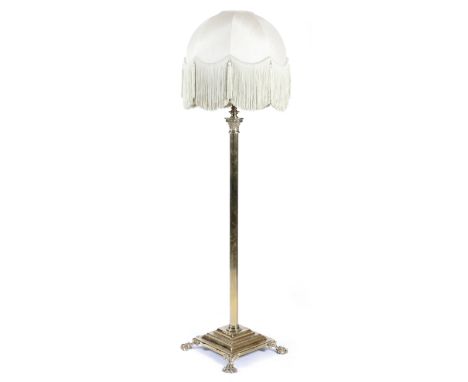 A brass Corinthian column standard lamp, with a reeded stem, on a stepped plinth and lion's paw feet, with shade, early 20th 