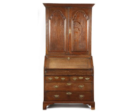 An early 18th century oak bureau cabinet, the moulded cornice above a pair of arched fielded panel doors enclosing two adjust