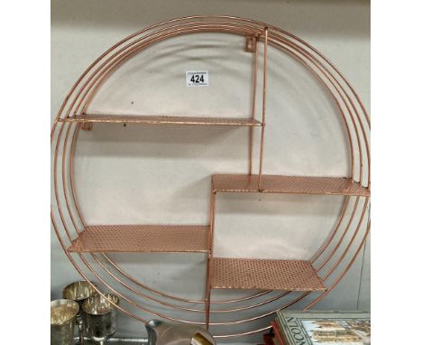 A circular copper coloured wall shelf unit