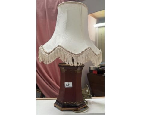 A wood effect lamp base with fringed shade