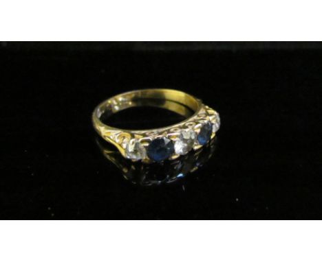 A gold ring set with three diamonds spaced by blue sapphires, marks rubbed. Size L, 3.1g