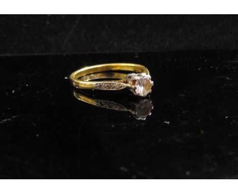 A gold solitaire ring the central clear stone with diamond set shoulders, stamped 18ct/platinum. Size N, 2.9g