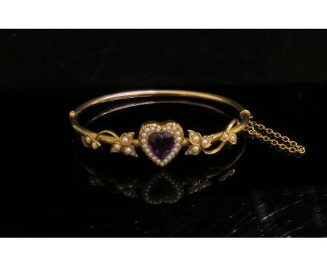 A gold bangle centrally set with heart shaped amethyst framed by seed pearls flanked by seed pearl ivy leaf decoration, stamp