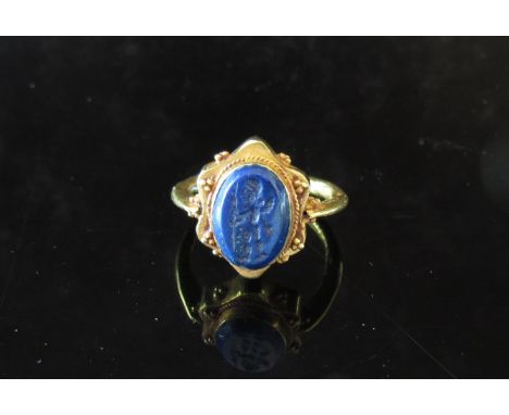 A gold Sasanian style ring with oval lapis intaglio of a walking cherub. Size P+, 5.9g     