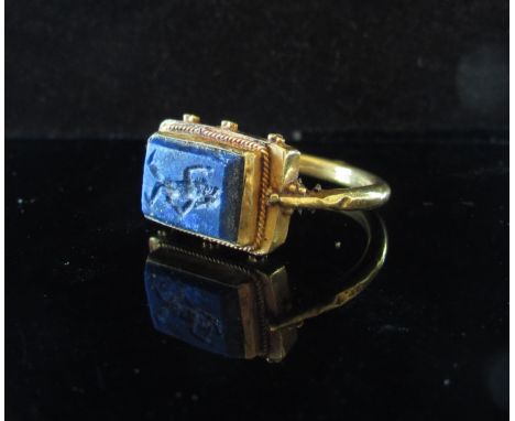 A gold Sasanian style ring with rectangular lapis intaglio of warrior. Size R, 5.9g  