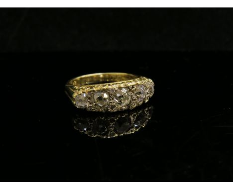 An 18ct gold ring set with five graduated diamonds and eight diamond chips in scroll mount, 1.20ct approx. Size M, 6.9g