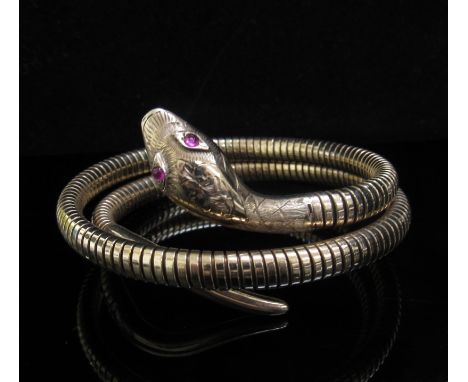 A 9ct gold sprung snake bangle with ruby set eyes and engraved decoration to head, 30.4g