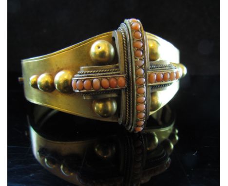 A Victorian gold bangle with raised frontis with coral set cross and domed decoration, unmarked, 24.9g