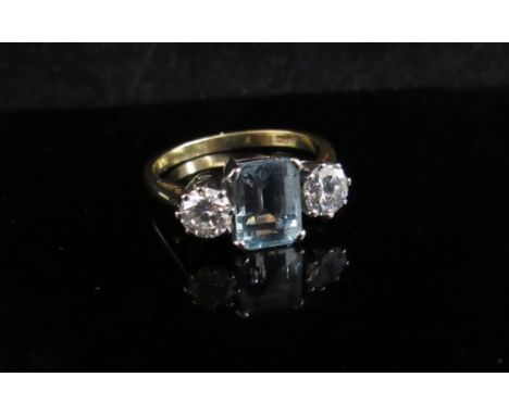 An aquamarine and diamond ring the central aqua 8mm x 5mm flanked by .45ct approx diamonds. Stamped 18ct. Size P, 4.1g