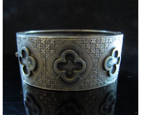 A stiff hinge bangle with stylised foliate decoration, stamped sterling, 31.3g