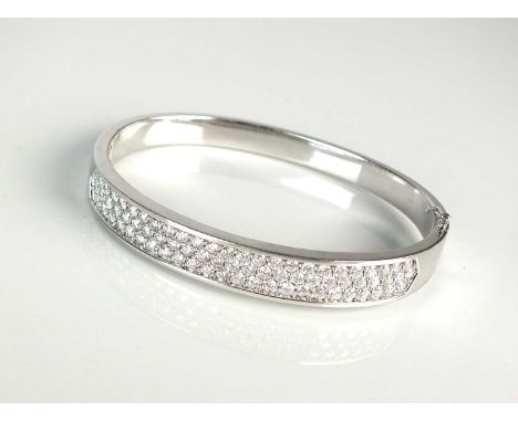 An 18ct white gold diamond set bangle, designed as three rows of brilliant cut diamonds all claw set in white gold to broad h