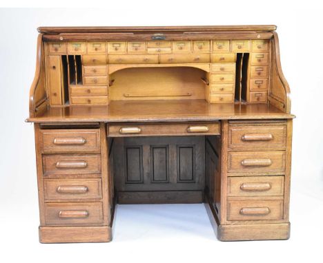 A 20th century oak roll-top pedestal deskThe top with tambour shutter enclosing multiple drawers and pigeonholes, the pedesta
