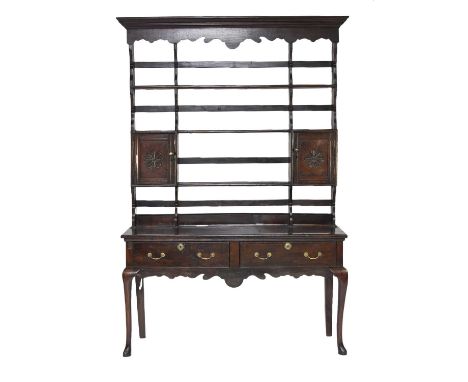 An 18th century oak dresser and rackThe open rack with ogee cornice and shaped apron above three shelves and twin spice cupbo