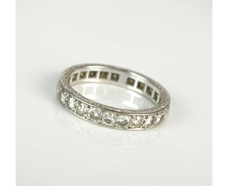 A diamond eternity band, the brilliant cut diamonds claw set in white metal to bright cut engraved band, ring size U, weight 