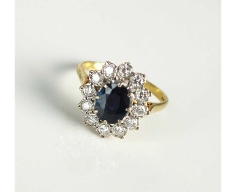 An 18ct gold sapphire and diamond oval cluster ring, designed as a central oval mixed cut sapphire claw set in white gold wit