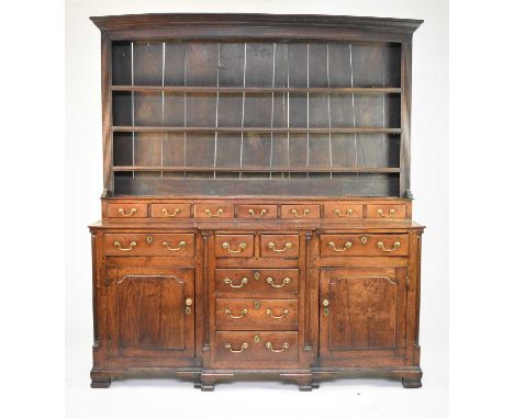 A George III oak breakfront dresser and rack, North WalesThe boarded rack with ogee cornice and three shelves above seven spi