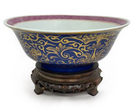 A Chinese powder blue and gilt porcelain bowl on a wooden stand. Diameter 23cm.The overall condition is good. There are no ch