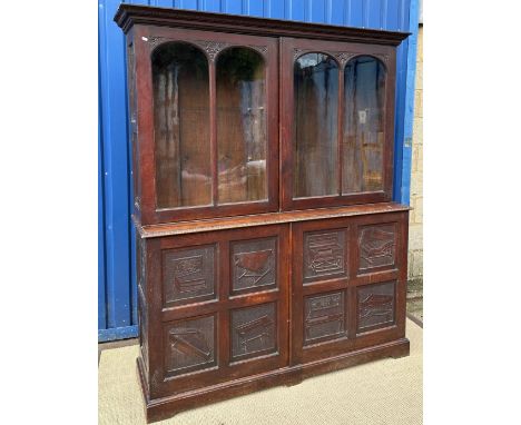 A Victorian oak bookcase cabinet, the upper section with foliate carved pediment over two pairs of twin arch panelled doors e