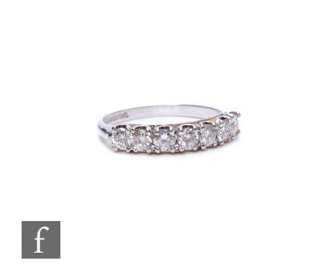 An 18ct hallmarked white gold diamond seven stone half eternity ring, brilliant cut, claw set stones, total weight approximat
